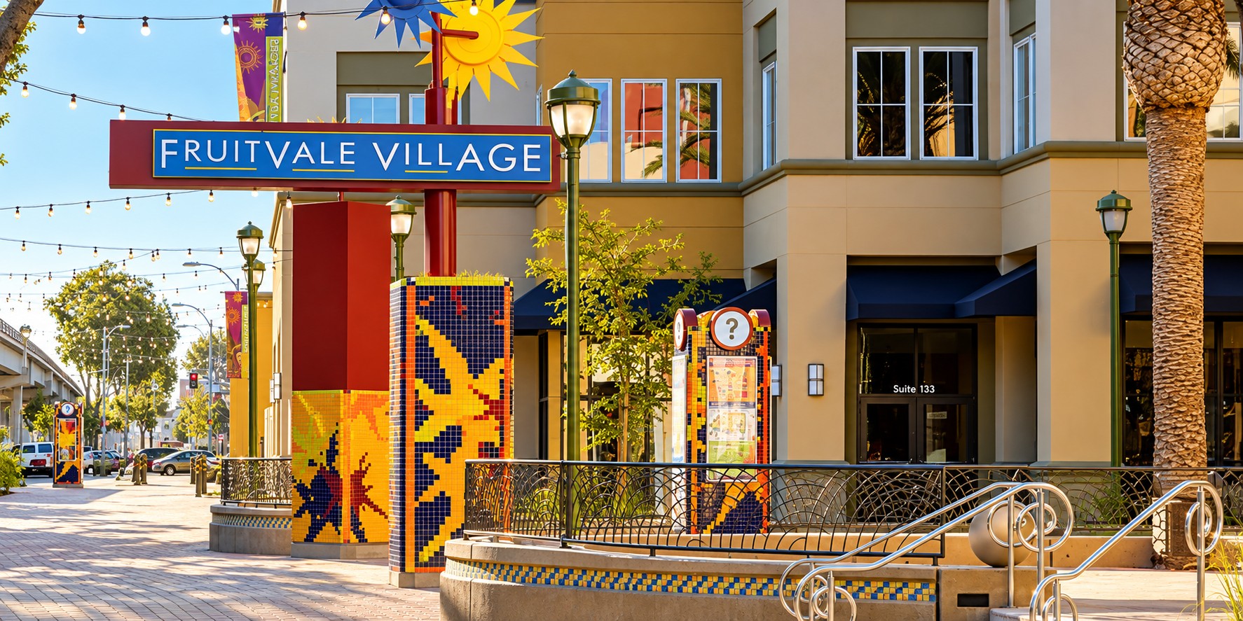 The colorful Fruitvale Transit Village plaza entrance in Oakland, California, with mosaic pillars and the Fruitvale Transit Village sign.